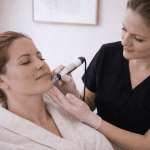 Patient receiving microneedling facial treatment from aesthetic provider
